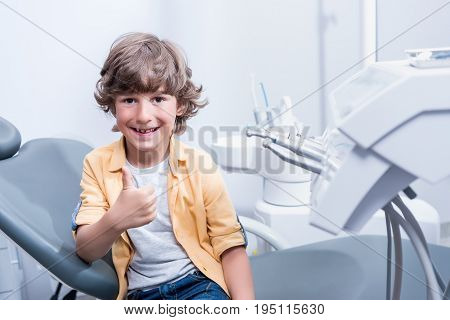 Portrait Of Little Smiling Boy Showing Thumb Up In Dental Clinic
