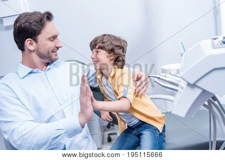 Portrait Of Dentist Giving Five To Little Boy In Dental Clinic