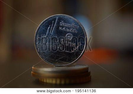 Macro detail of a Thai coin (Thai baht, THB) on the top of column created of coins with a positive colorful warm background