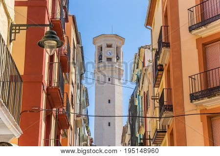 ALCOY, SPAIN - JUNE 14, 2017: Colorful street and tower of the Sant Maure and Francesc church in Alcoy, Spain