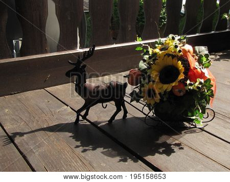 A wooden deer on a wooden floor with a flower holder