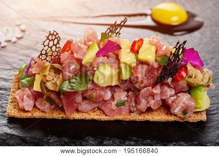fresh tuna tartar with salt and herbs, studio shot. Fish tartar on black shale. Close-up