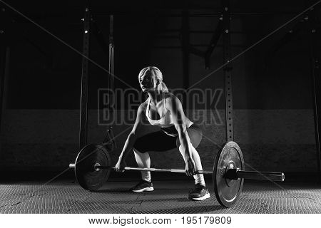 Muscular young fitness woman lifting a weight crossfit in the gym. Fitness woman deadlift barbell.
