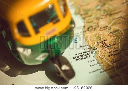 Mumbai city on Indian map with driving toy model of traditional auto-rickshaw vehicle. Symbols of old India.