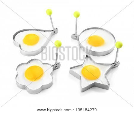 Fried sunny side up eggs in molds of different shapes isolated on white