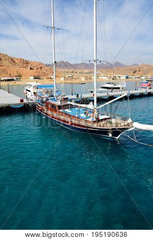 SHARM EL SHEIKH EGYPT - DECEMBER 4: The sail yacht with tourists is near pier in harbor of Sharm el Sheikh. It is popular tourists destination on December 4 2013 in Sharm el Sheikh Egypt