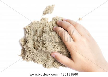 Child playing with kinetic sand. Hand of the child in the sand close up on a bright background