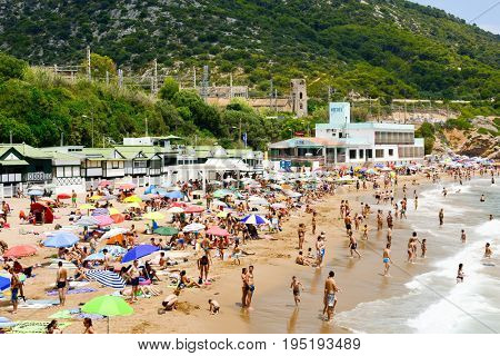 SITGES, SPAIN - JULY 9, 2017: People enjoying, relaxing, sunbathing or bathing at the Garraf Beach in Sitges, a popular beach in the coast of the Metropolitan Area of Barcelona, in Catalonia