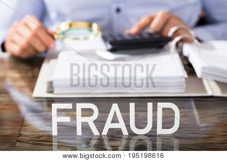 Close-up Of Financial Data Analyst With Fraud Text On Glass Desk In Office