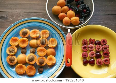 Plates With Apricots And Cherries And Colander Full Of Berries