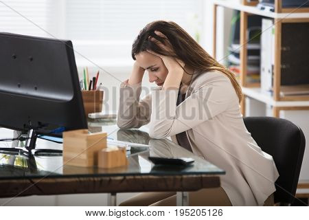 Young Businesswoman Suffering From Headache At Workplace