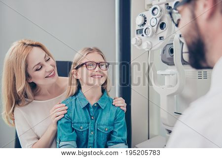 Healthcare, People, Eyesight And Vision Concept. Small Cute Blond Girl Is Trying On Glasses, Mom And