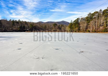 Frozen wintry landscape of cracked ice full of holes at Lake Powhatan in North Carolina