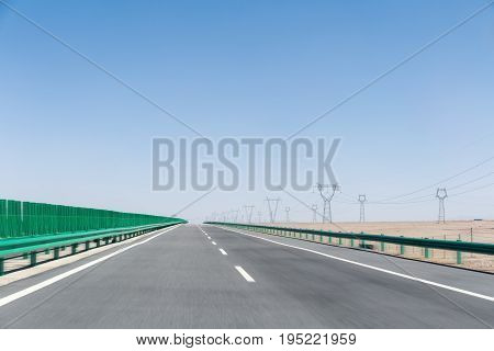 highway on gobi desert road motion blur with power transmission tower on wilderness background