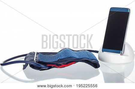 Electronic smart blood pressure monitor or sphygmomanometer with a phone or tablet hooked up to an inflatable arm cuff. This device is the modern version of the traditional medical instrument for health care.