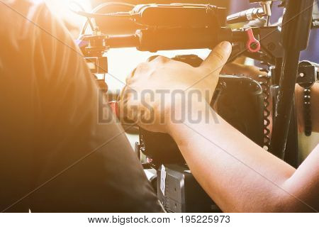 Cameraman with his video camera shooting, Hands Adjusting Camera,film production crew, behind the scenes background.
