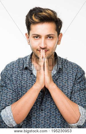 Portrait of good looking Indian or asian young man in casual dressing with folded hands against background