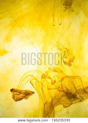 Ink swirl in a water on yellow background. The paint splash in the water. Soft dissemination a droplets of colored ink in water close-up. Abstract background. Explosion of color splashes acrylic ink.