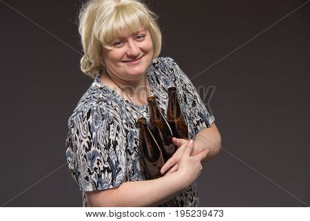 Lonely poor fat woman aged drinking beer and eating fish.