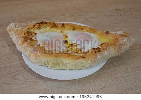 Adjarian Khachapuri - georgian cheese pie with egg. Adjarian khachapuri on a on a plate. Open pie with cheese in the shape of the boat