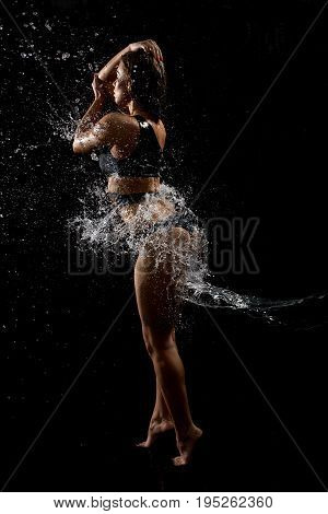 Young sexy fitness model in fashionable swimsuit posing in water splashes studio shot
