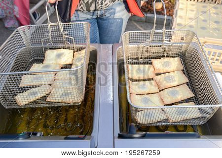 Agno, Switzerland - 12 March 2016: Street vendor while he is cooking the tasty pancakes dipped in boiling oil