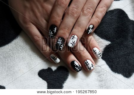 Hands of a young girl with black and white manicure