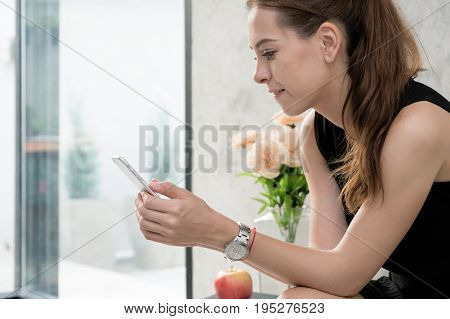 Portrait of happy young woman with mobile phone sitting on couch at home