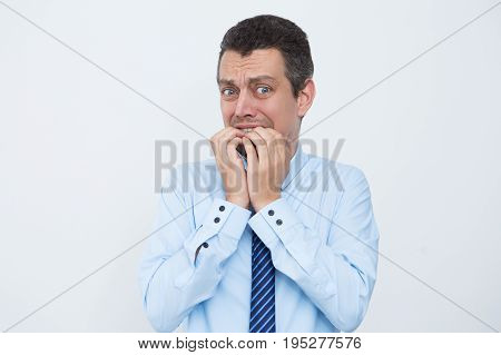 Anexious young businessman chewing fingernails when worrying. Emotional male manager before meeting. Nervous entrepreneur looking at camera. Stress concept