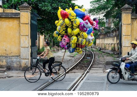 Hanoi, Vietnam - August 16, 2015: a young Vienamese helium balloon saleswoman on a bicycle, selling Despicable Me balloons in the Old Quarter.