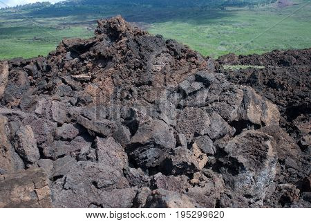 View of Black lava rocks line the shore at Keanae on the road to Hana in Maui, Hawaii