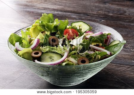 Bowl Of Salad With Vegetables And Greens On Wooden Table