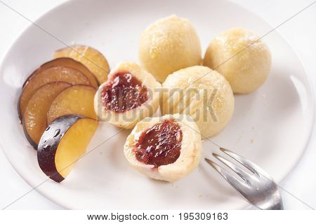 Close up of austrian popular dish called knoedel with plum jam and cinnamon on white plate