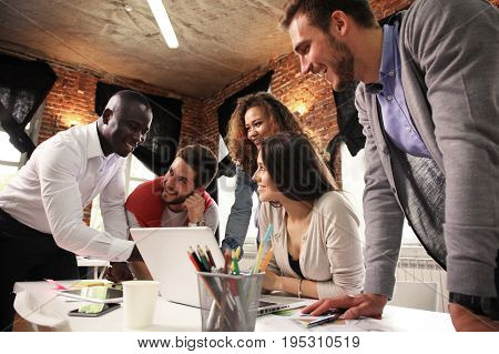 Teamwork concept.Young creative coworkers working with new startup project in modern office.Group of people analyze data on desktop computer.