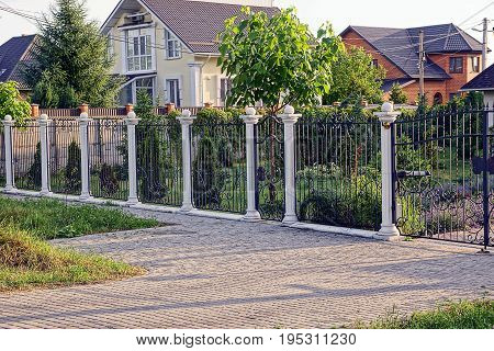 Black-white fence with a wicket in front of a private garden and a house on the street