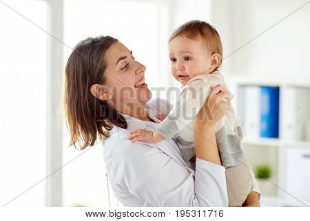 medicine, healthcare, pediatry and people concept - happy doctor or pediatrician holding baby on medical exam at clinic