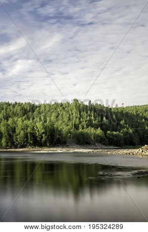 Ljungan River in Sweden with forest and a cloudy sky.