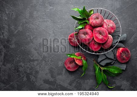 Peaches with leaves on dark background, top view