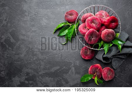 Peaches with leaves on dark background, top view