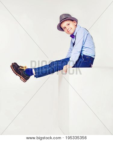 happy stylish boy wearing a hat and a tie, against white background