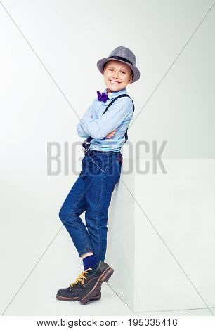 happy stylish boy wearing a hat and a tie, against white background