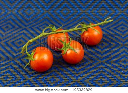 Juicy tomatoes on a green branch against the background of a gossip bamboo cloth