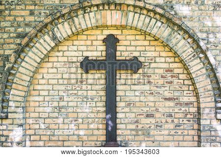 old metal cross on brick wall background - rusty cross on grave