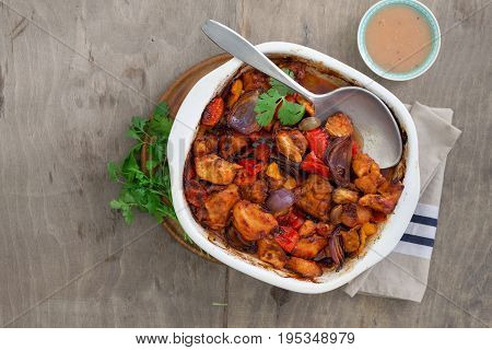 Baked chicken breast with vegetables and sauce on rustic wooden table with copy space top view. Dinner table concept