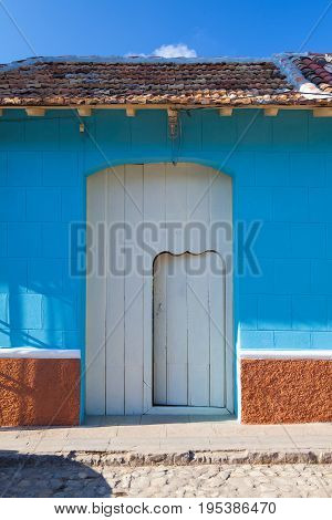 Typical colonial building with small door in the big gate Trinidad Cuba