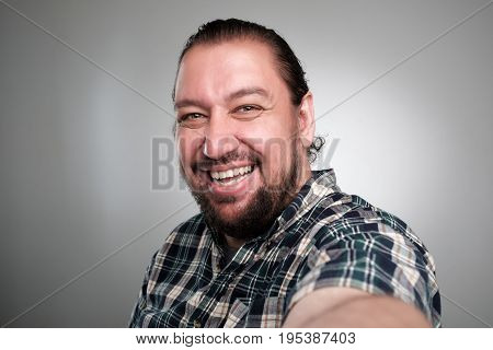 Beautiful young man in casual clothes make selfie on a gray background.