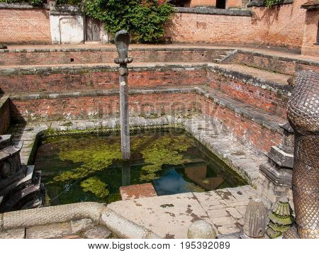 KATHMANDU, BHAKTAPUR, NEPAL. 30 September 2008: Naga Pokhari (Snake Pond) in The Palace of fifty five Windows in Bhaktapur's Durbar Square is a royal water tank encircled by a writhing stone cobra.