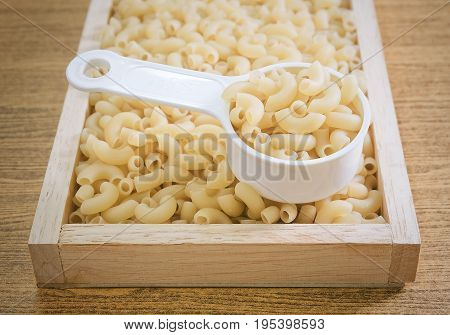 Food and Cuisine Uncooked and Dried Elbow Macaroni or Gomiti Pasta in Plastic Measuring Cup.