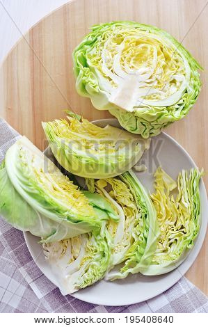 fresh green cut head of cabbage on ceramic gray plate, wooden and material background