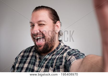 Beautiful young man in casual clothes make selfie on a gray background.